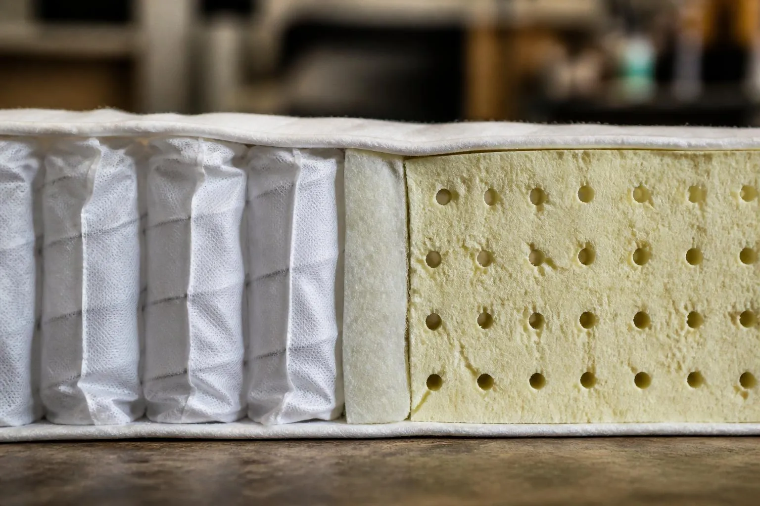 Coupe transversale d'un matelas, ressorts ensachés dans leurs sachets de tissu d'un côté, bloc de mousse alvéolaire de l'autre.